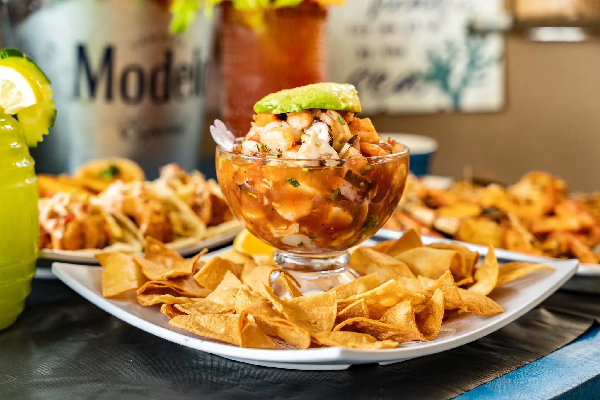 Wacky Crab Shack ceviche with fresh avocado in a footed glass, surrounded by crispy tortilla chips and a Modelo bucket