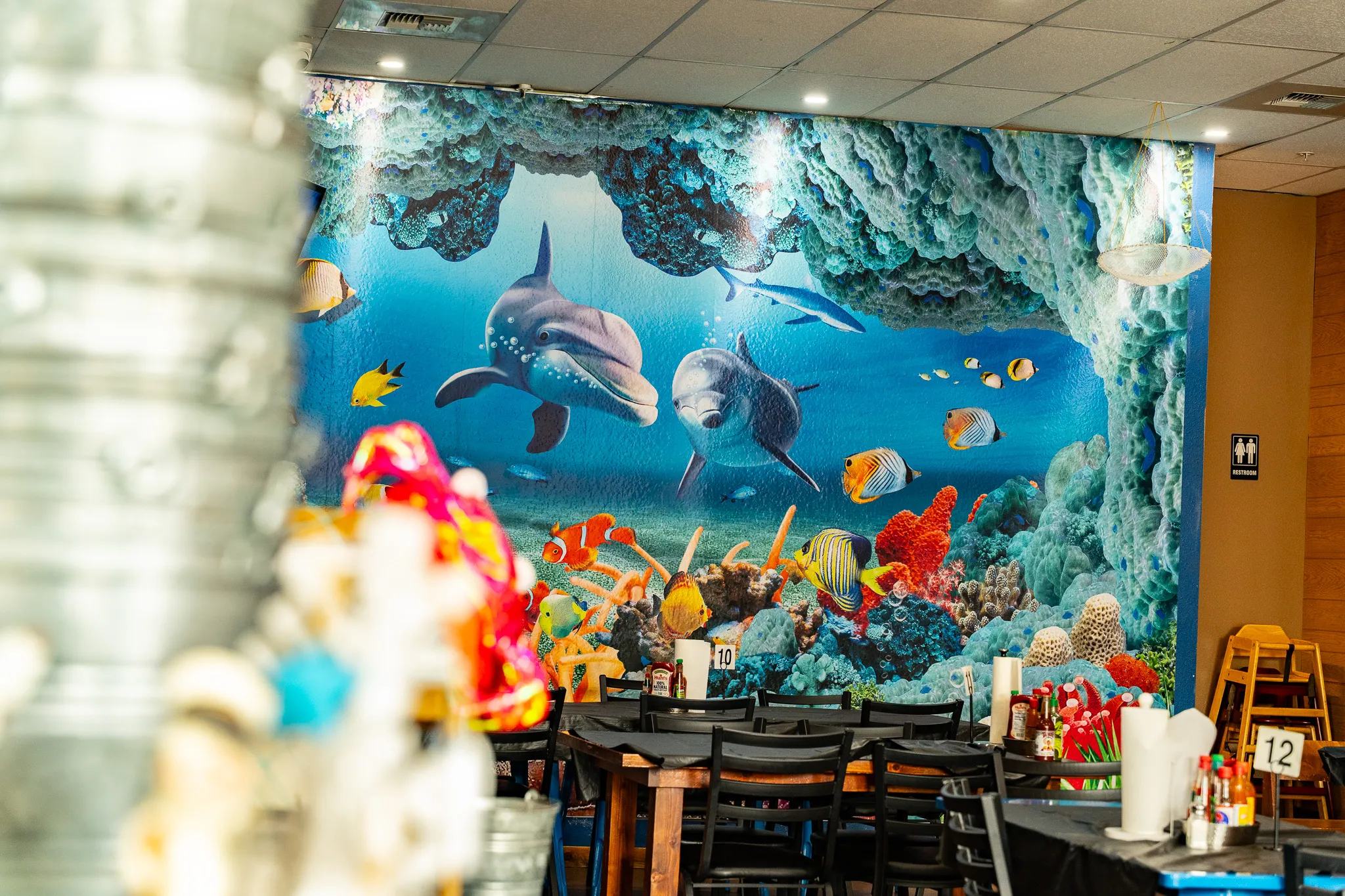 The Wacky Crab Shack dining room with a large painted mural of dolphins swimming through a coral reef
