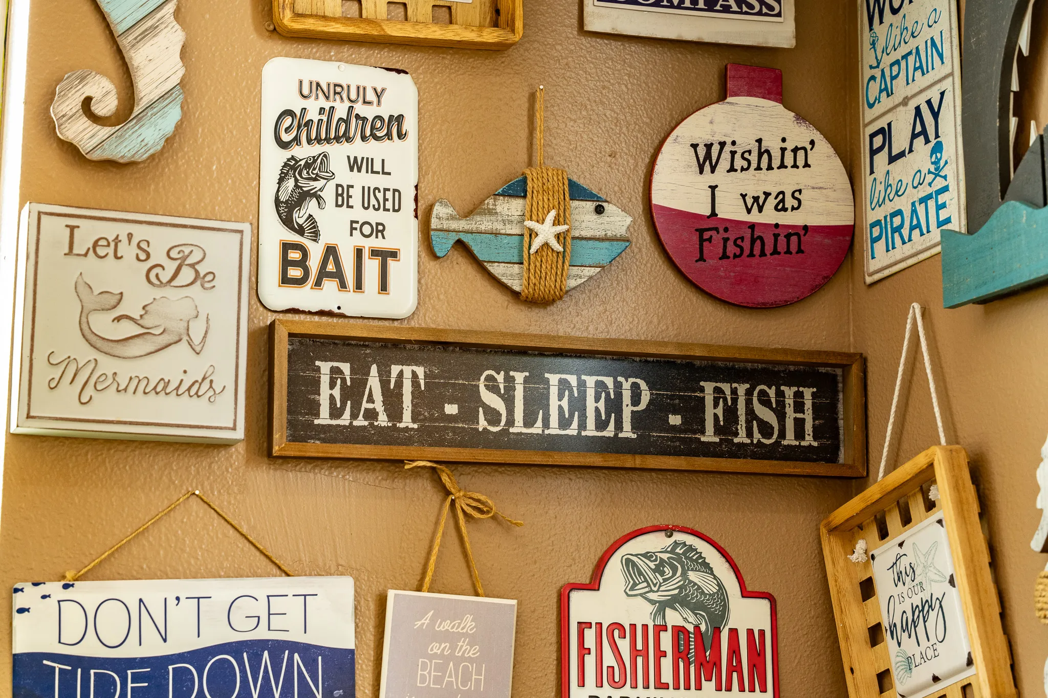 A wall of playful hand-painted signs at Wacky Crab Shack: "Eat Sleep Fish," "Let's Be Mermaids," and "Unruly Children Will Be Used For Bait"