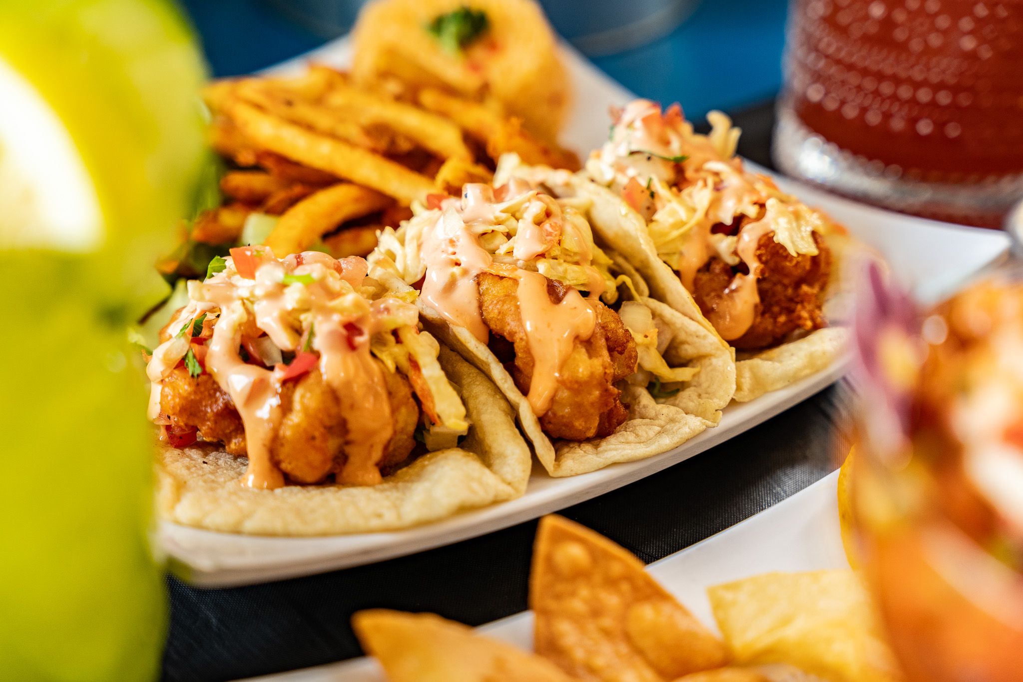 A trio of crispy Wacky Crab Shack shrimp tacos drizzled with creamy sauce and topped with slaw and pico